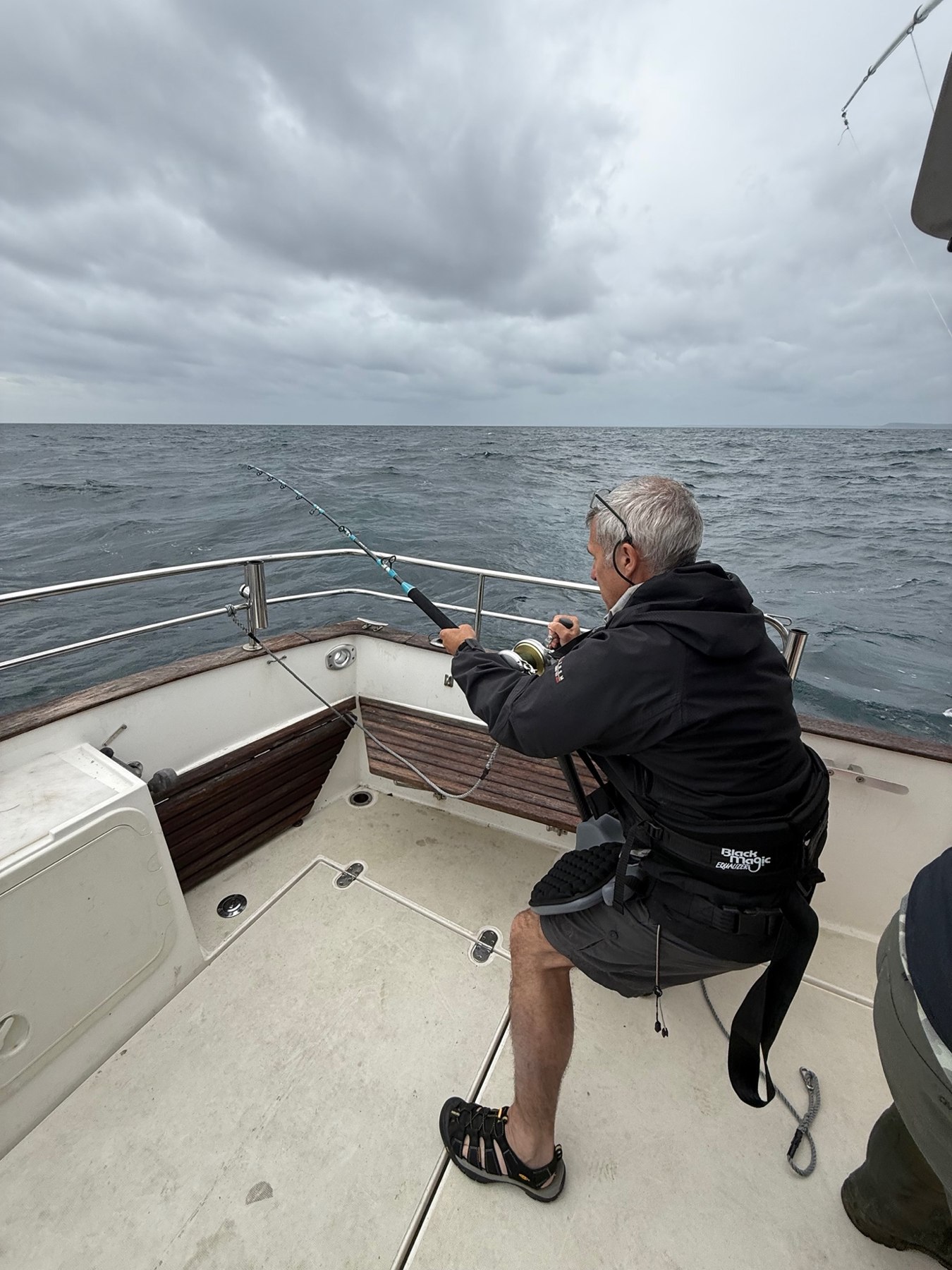 An angler working a fishing rod on deck